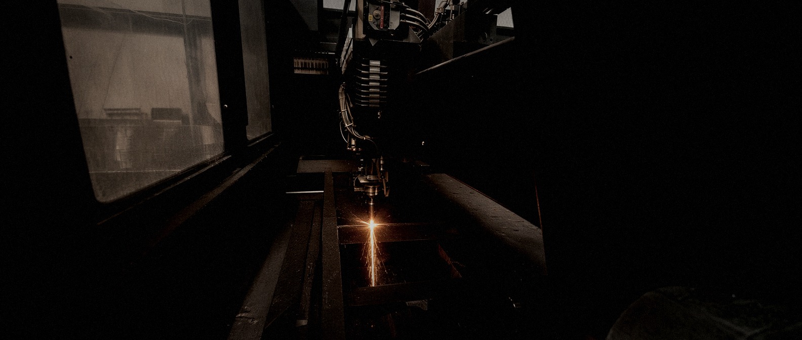 Fiber laser cutting head sparks as it cuts through a steel sheet
